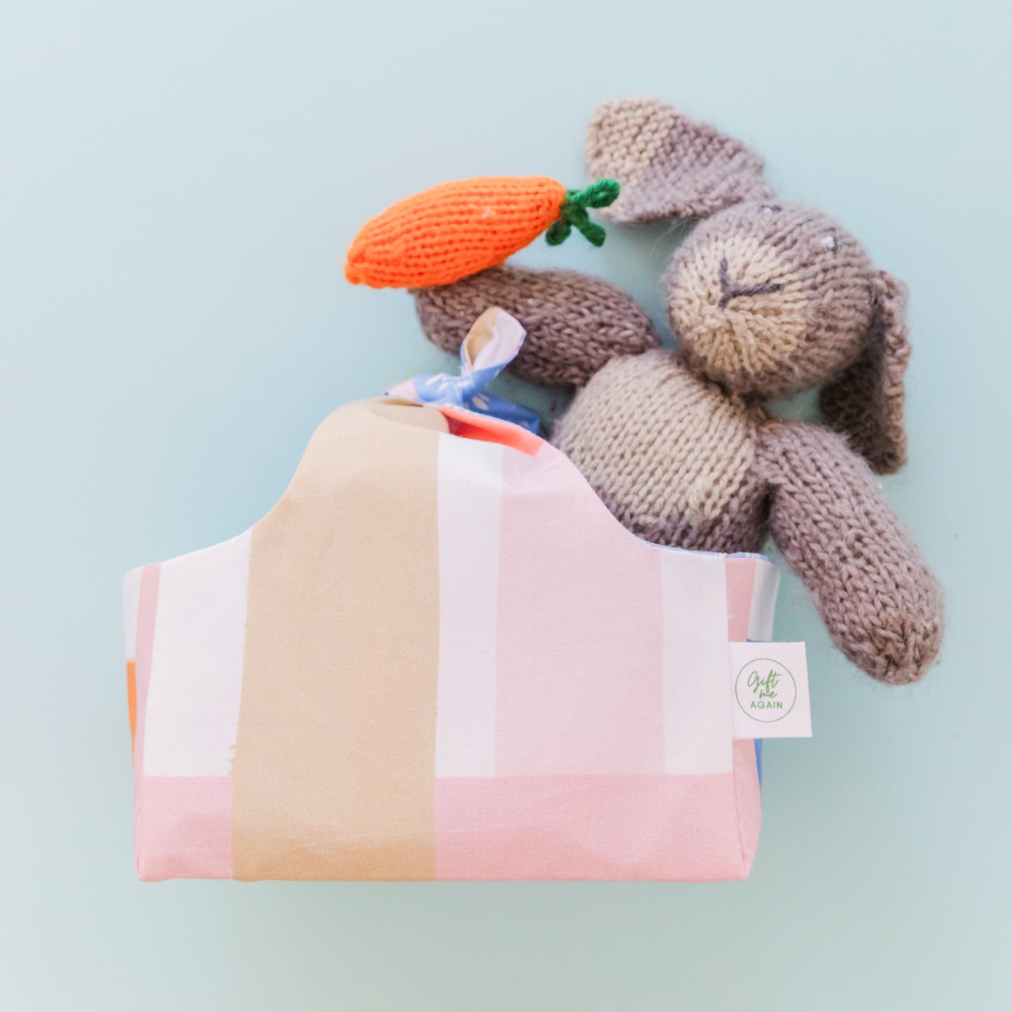 A fabric Easter basket in a pastel paid print with a knitted woolen bunny inside.