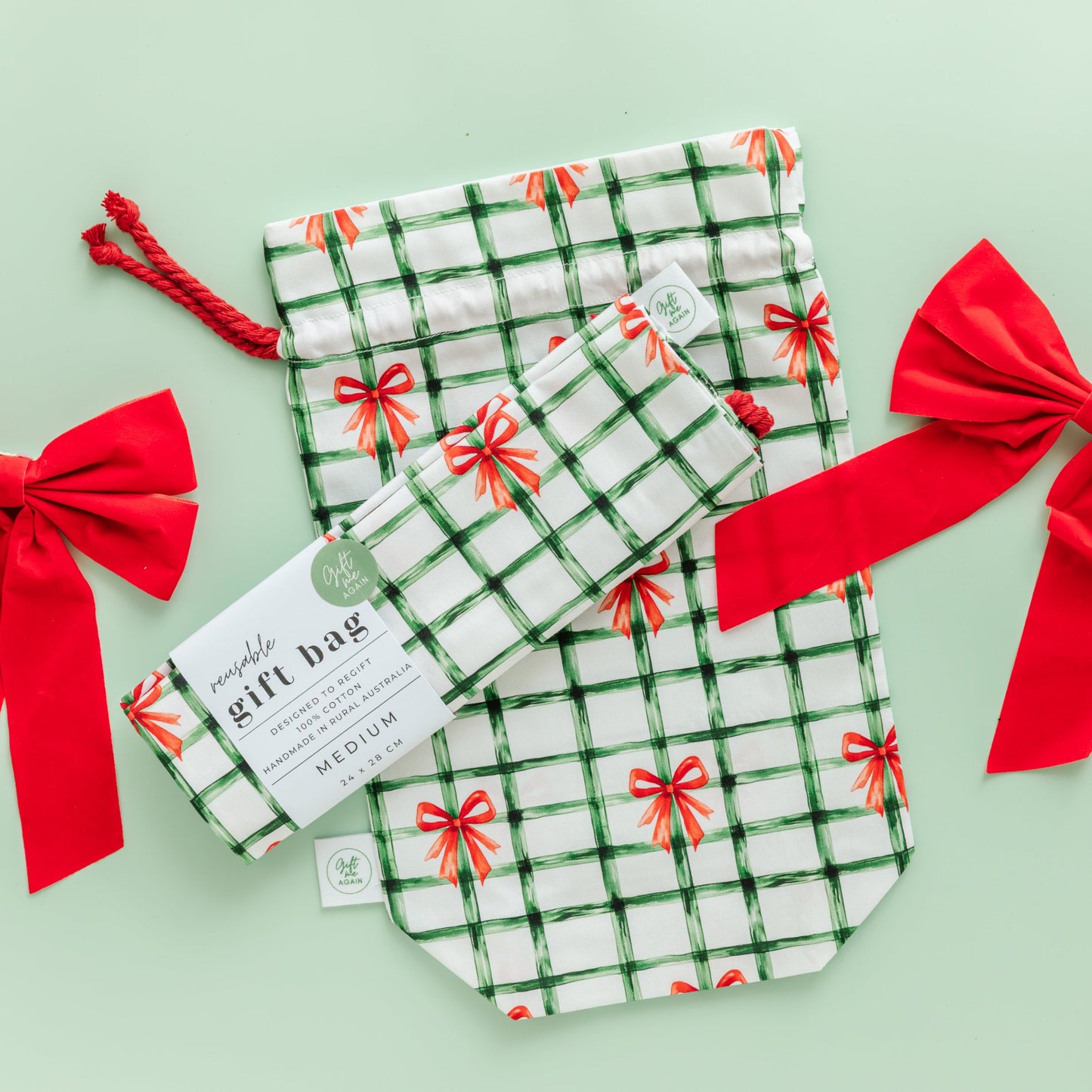 Set of fabric gift bags with red bows on a light green background