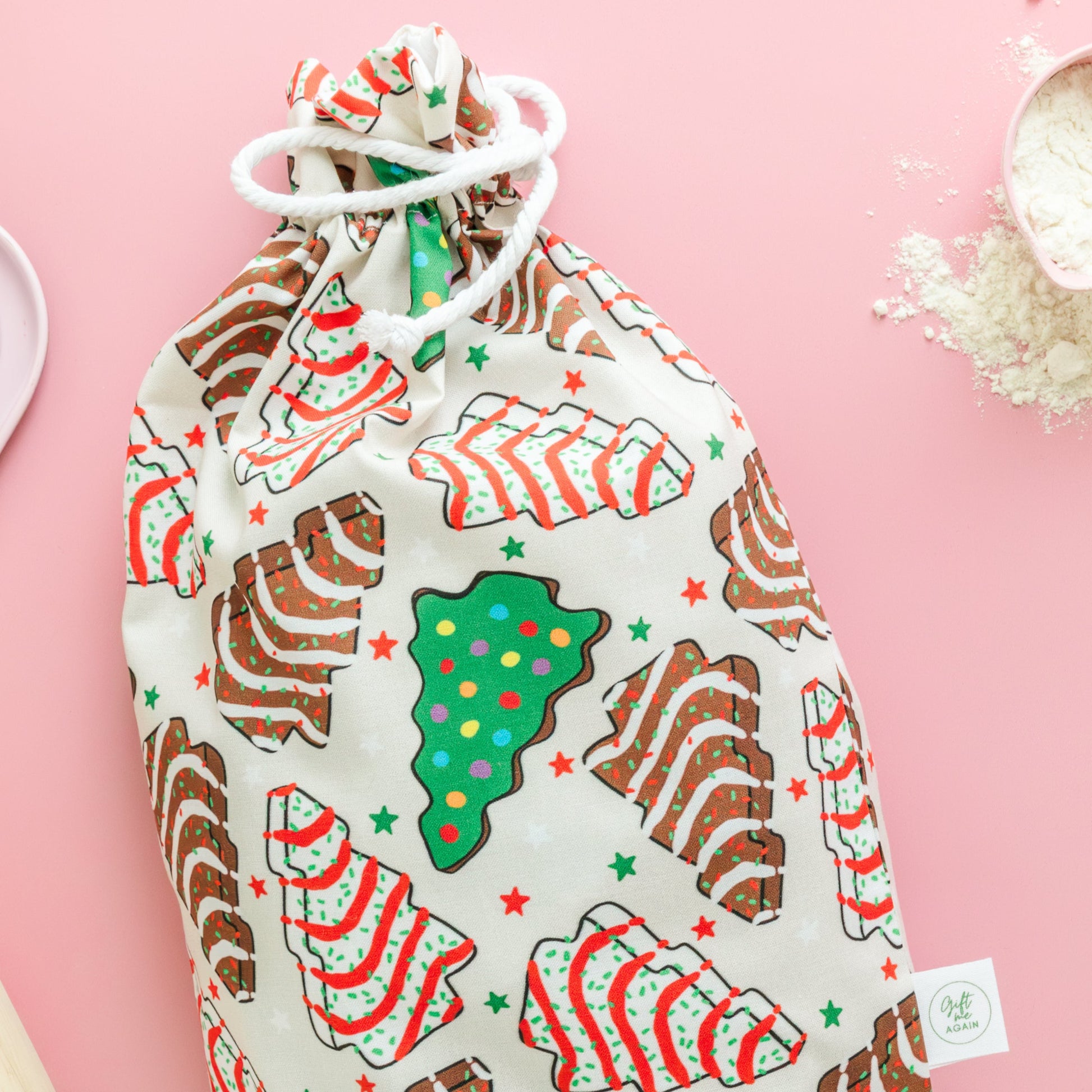 Fabric gift bag with Christmas-themed cookie print on a pink background