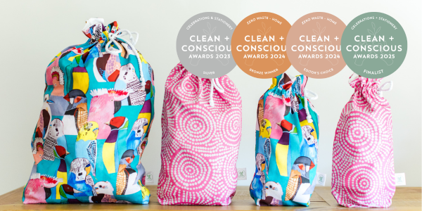 Four reusable gift bags in vibrant prints, displayed in size order, with Clean + Conscious Awards medals showcasing sustainability recognition from 2023 to 2025.