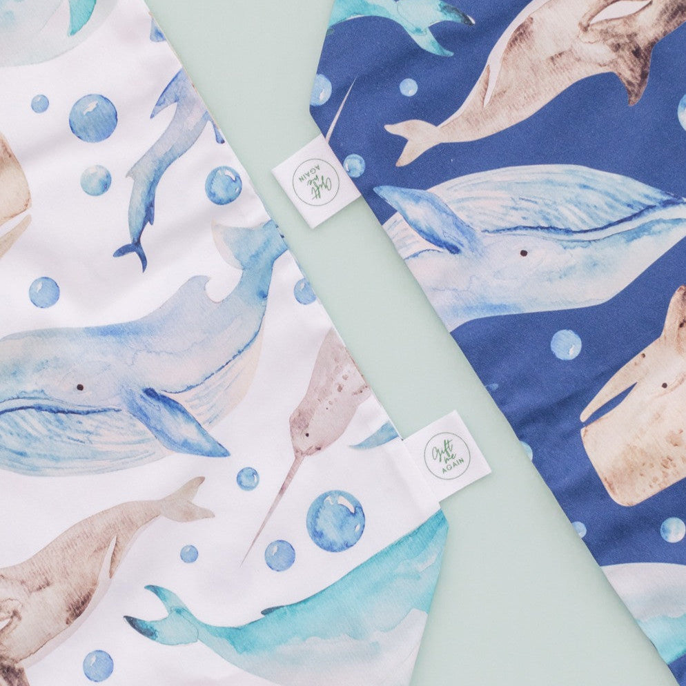 Close-up of two reusable fabric gift bags with marine animal prints, including whales, narwhals, and dolphins. Handmade by Gift Me Again, perfect for eco-friendly gifting.