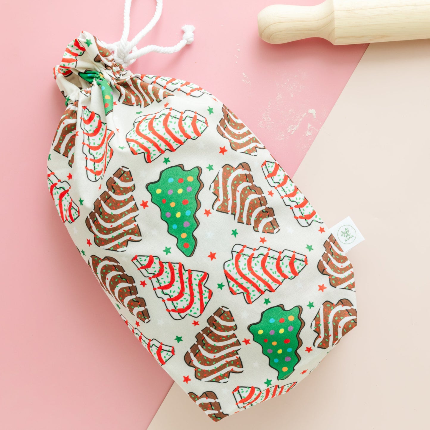 Drawstring gift bag with Christmas-themed cookie design on a pink background