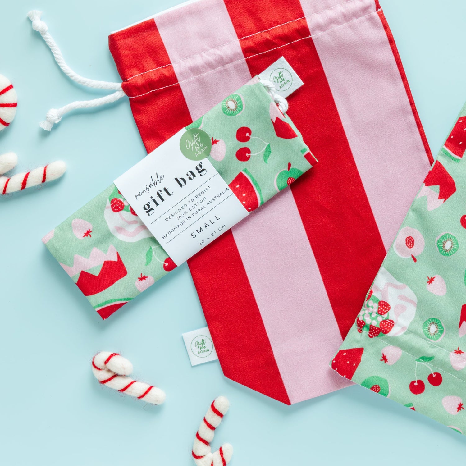 Red and pink striped gift bag with a green patterned tag on a light blue background