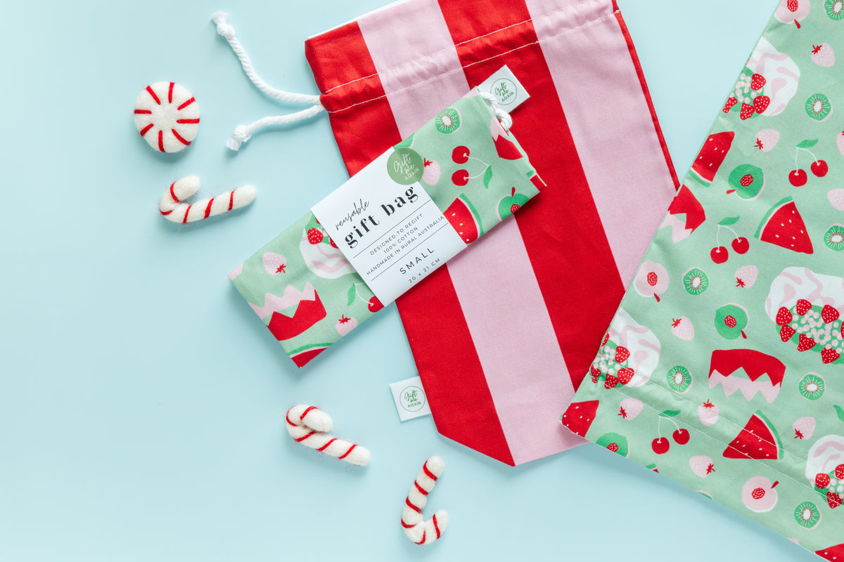 Red and pink striped gift bag with a green patterned tag on a light blue background
