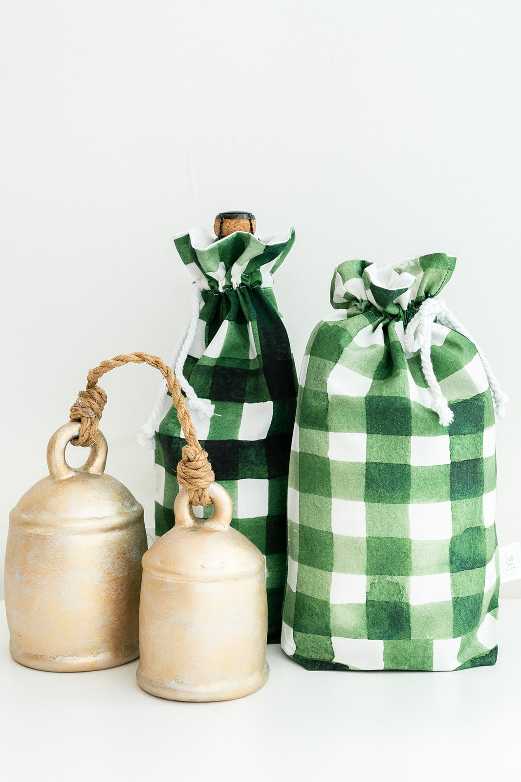 Three green and white check drawstring gift bags with rope handles, arranged on a clean white background.